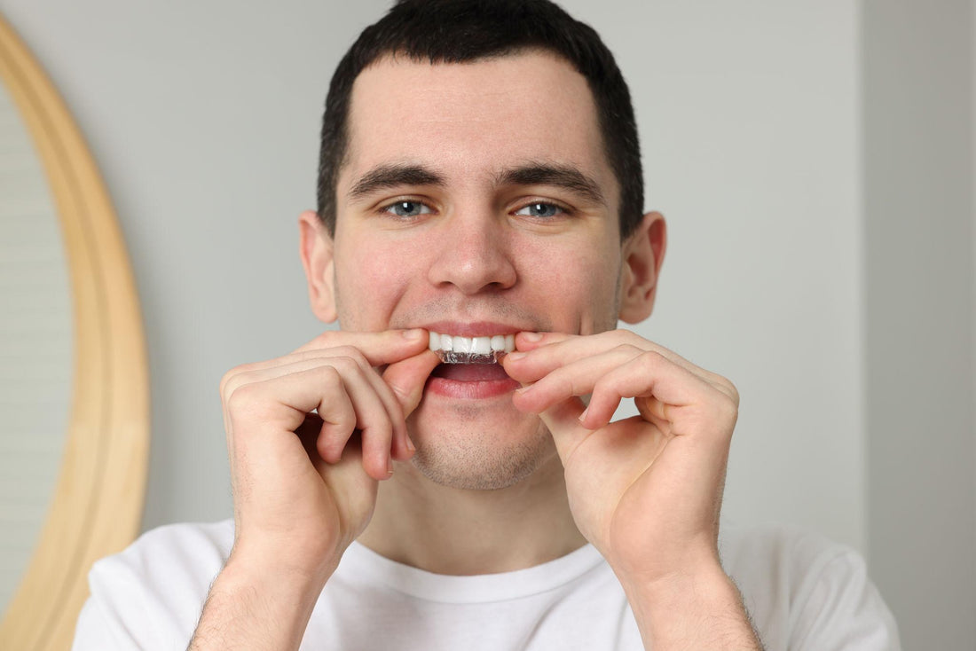 Man die whitening strips op zijn tanden aanbrengt voor wittere tanden zonder tandgevoeligheid